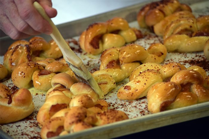 brushing bacon breadsticks with butter