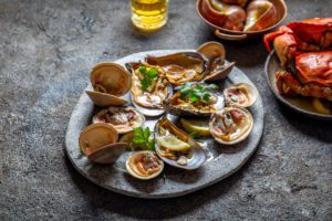 Raw seafood, crabs, clams and mussels shellfish with lemon and cilantro on gray plate shellfish